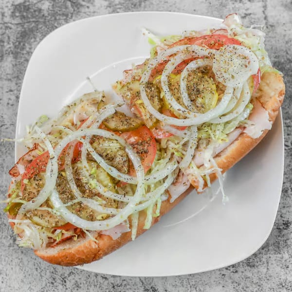 A Milan's Real Philly Cheesesteaks and Hoagies hoagie, topped with onions, tomatoes, and spices.