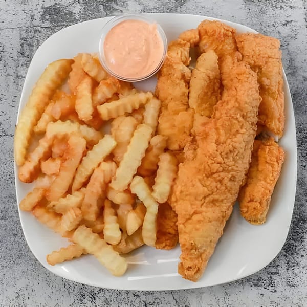 Crispy fried chicken tenders and crinkle-cut fries with a side of dipping sauce on a white plate.
