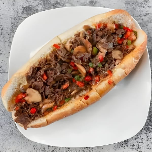 Milan's Real Philly Cheesesteak with steak, mushrooms, red and green peppers on a white plate.
